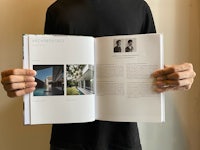 a man holding an open book with a picture of a house