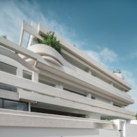 a white apartment building with balconies and plants