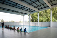 a group of people sitting on the edge of a swimming pool