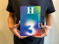 a man holding up a book with the word h on it