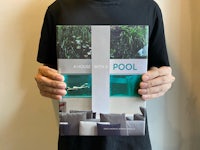 a man holding up a book with a picture of a pool