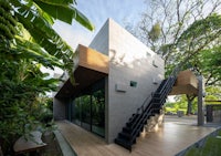 a modern house in the jungle with stairs leading up to it