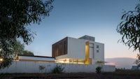 a modern house in the middle of a field at dusk