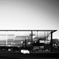 a black and white image of a building with a car in front of it