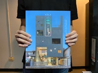 a man holding up a book with a picture of a building