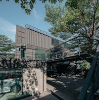 a black shipping container house with a tree in the background