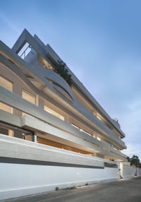 a modern apartment building on a street at dusk