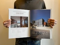 a man holding up a magazine with a picture of a house